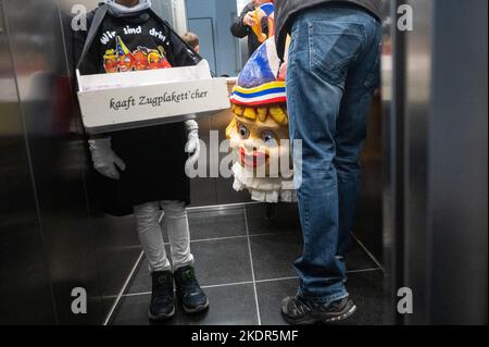 Magonza, Germania. 08th Nov 2022. Un uomo mette la testa di una testa di Kinder-Schwellkopp, o testa di caricatura sovradimensionata, in un ascensore dopo la presentazione delle targhe di Mainzer Carneval-Verein (MCV) per la prossima stagione di carnevale. Le targhe possono essere acquistate a partire dalla riunione di inizio del Mainzer Fasnacht del 11/11. Esse rappresentano la principale fonte di finanziamento per Mainzer Straßenfastnacht. Credit: Sebastian Gollnow/dpa/Alamy Live News Foto Stock