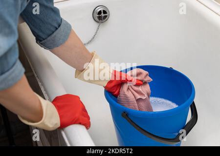 la mano toglie uno straccio bagnato da un secchio di acqua. la mano stringendo fuori uno straccio bagnato. Foto di alta qualità Foto Stock