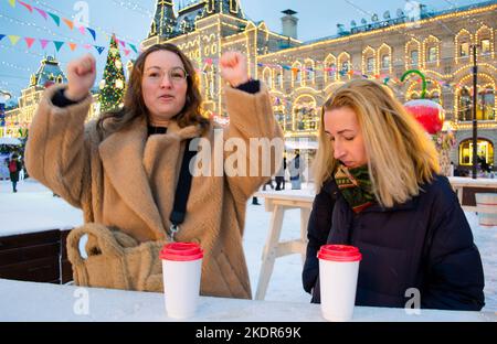 Giovane donna allegra con tazza di cartone con bevande calde danzare e ridere. Fiera di Natale a Mosca sulla Piazza Rossa. Foto Stock