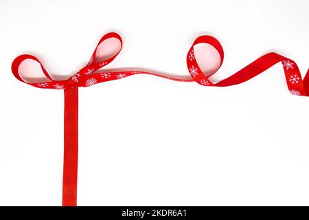 Un arco di rosso arricciante nastro luminoso con fiocchi di neve come cornice. Sfondo bianco, spazio di copia. Il concetto di Natale, San Valentino, regali. Foto Stock