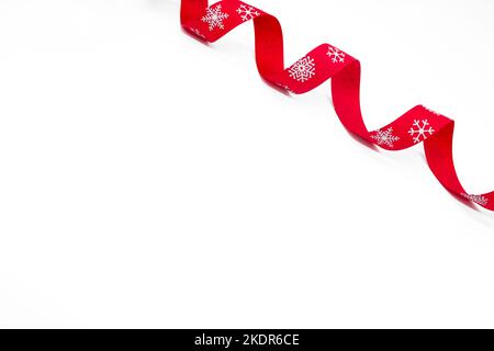 Un nastro rosso riccio luminoso con fiocchi di neve su sfondo bianco. Spazio di copia. Il concetto di Natale, San Valentino e regali. Foto Stock