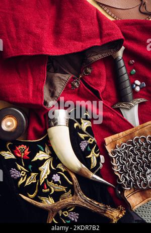 Gioco di ruolo fantasy dal vivo. Sfondo decorato con vari oggetti carattere strumenti: Pugnale, catena di posta, capo, abbigliamento, corno. Foto Stock