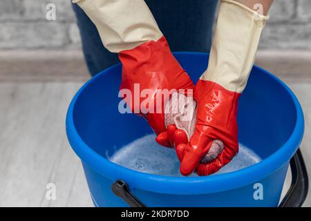 donna che strizzava un panno bagnato in un secchio. mano che strizzava un panno bagnato. Foto di alta qualità Foto Stock