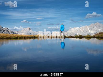 Donna e montagne si riflettevano nel lago al tramonto in autunno Foto Stock