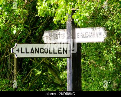 Cartello in legno che mostra in tre direzioni per Birmingham, Llangollen e Chestet. Fotografia scattata all'incrocio di Hurleston. Foto Stock