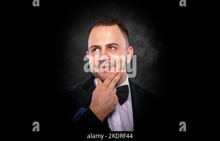 Bel giovane uomo alla moda su sfondo scuro. Foto Stock