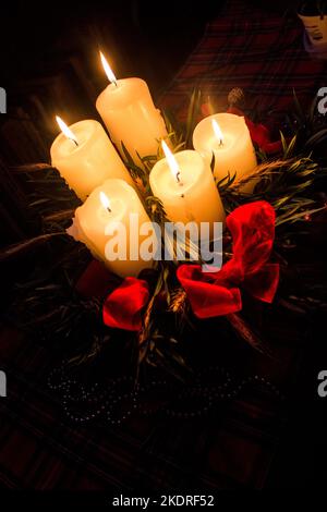 Una corona avvento completamente illuminata con cinque candele al buio. Foto Stock