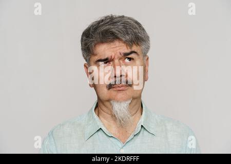 Uomo perplesso senior con baffi e barba che guarda verso l'alto isolato su sfondo bianco Foto Stock