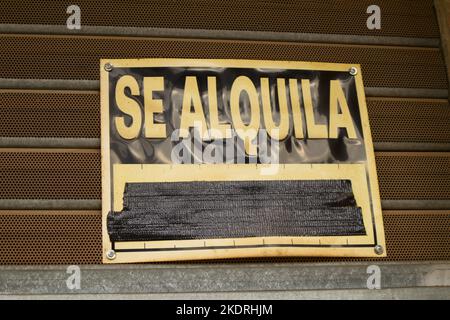 Primo piano di un cartello attaccato all'otturatore di un negozio che indica che i locali sono in affitto scritto in spagnolo ('se Alquila') Foto Stock