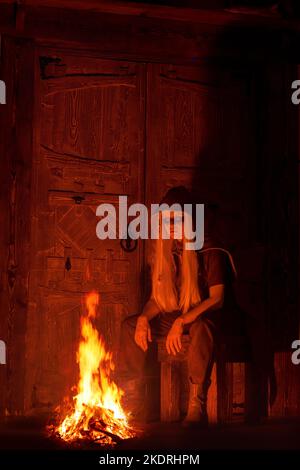 Donna vichinga in abiti da guerriero tradizionali. Donna vichinga all'interno di capanna di legno. Foto Stock