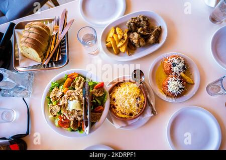 Famiglia mangiare cibo tradizionale greco in taverna ristorante in Grecia. In una taverna greca vengono serviti piatti tradizionali greci su autentici tavoli da pranzo e. Foto Stock