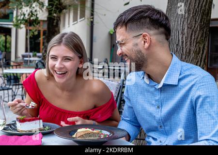 Felice coppia romantica ridendo e avendo un buon tempo a cena o pranzo in un bel ristorante all'aperto. Foto Stock