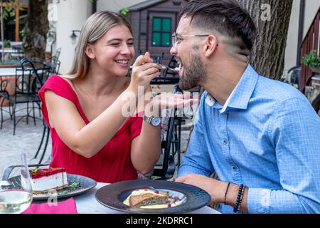 Felice coppia romantica che si nutre con dessert dopo cena o pranzo in un bel ristorante all'aperto. Foto Stock