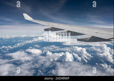 Ala di aeroplano sopra la superficie piana delle nuvole lanuginose con la luce solare morbida della sera. Spazio di copia. Foto Stock