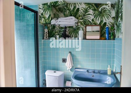 Elegante bagno interno in blu. Carta da parati con felci sul muro Foto Stock