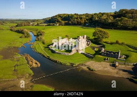 Veduta aerea delle pietre a gradini che attraversano un piccolo fiume che conduce ad un antico castello in rovina (Ogmore, Glamorgan, Galles) Foto Stock