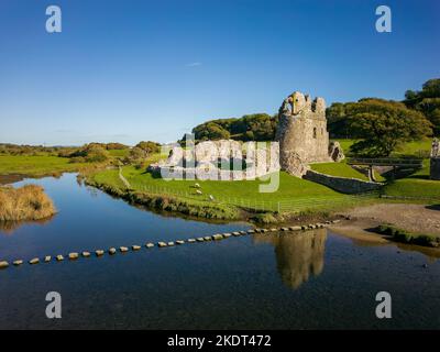 Veduta aerea delle pietre a gradini che attraversano un piccolo fiume che conduce ad un antico castello in rovina (Ogmore, Glamorgan, Galles) Foto Stock