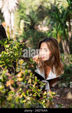 Giovane donna che indossa un abito bianco nero che esamina una pianta di giada | succulento Foto Stock