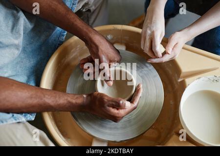 Vista dall'alto di una giovane coppia che utilizza la ruota in ceramica insieme e crea ceramiche fatte a mano Foto Stock