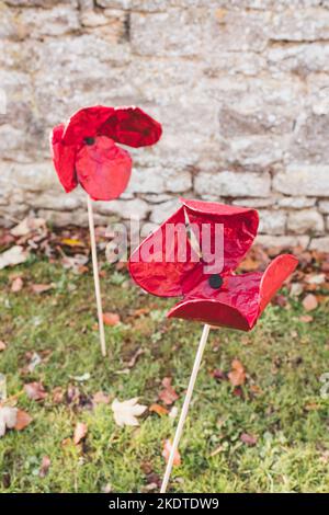 Papaveri di ceramica spinti nel terreno nel cimitero della Chiesa di Santa Maria, Witney per la Giornata della memoria Foto Stock