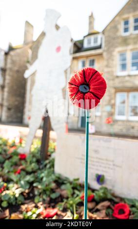 Papavero lavorato a maglia su un fusto spinto nel terreno nel cimitero della Chiesa di Santa Maria, Witney per il giorno della memoria Foto Stock