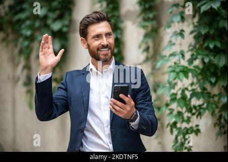 Elegante giovane uomo che saluta qualcuno e agitando la mano Foto Stock