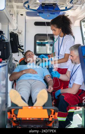 Team paramedico che fornisce assistenza medica di emergenza a una persona malata Foto Stock