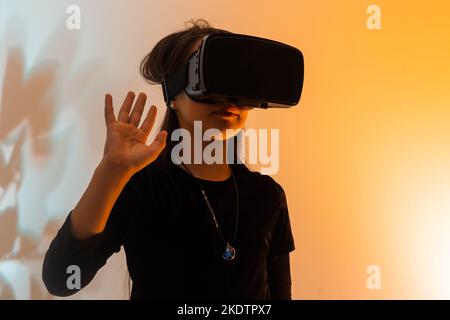 una bambina stupita indossa occhiali vr utilizzando la tecnologia per l'istruzione nella realtà virtuale, nel mondo virtuale. Banner di bambina con realtà virtuale vr Foto Stock