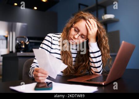 Donna infelice calcola le spese sulle fatture, sconvolto circa i prezzi aumentati delle utenze. Paghe, debiti, prestiti, ricevute per pagare le tasse Foto Stock