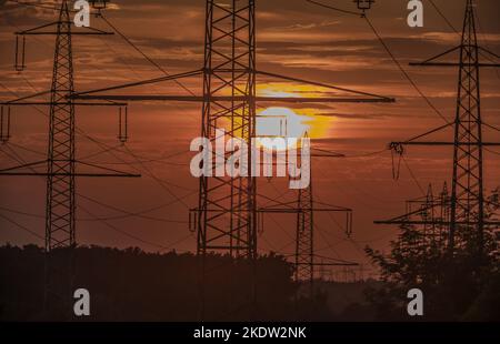 Poli di alimentazione davanti al tramonto in controluce Foto Stock
