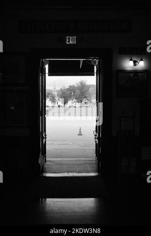 Guardando fuori attraverso la porta d'ingresso della stazione ferroviaria panoramica di Conway a North Conway, New Hampshire. L'immagine è stata catturata su bianco e nero analogico Foto Stock