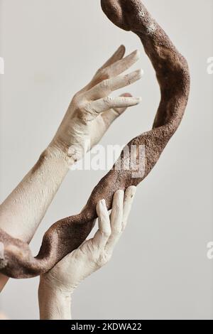 Primo piano di mani eleganti ricoperte di vernice che tiene pezzo d'arte ceramica minimo Foto Stock