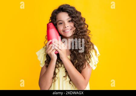 Bambina adolescente che mostra i balsami dello shampoo della bottiglia o il gel della doccia. Prodotto cosmetico per capelli. Bottiglia per la pubblicità mock up spazio copia. Felice Foto Stock