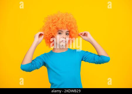 Bella ragazza adolescente in parrucca isolato su giallo. Parrucca clown divertente. Foto Stock