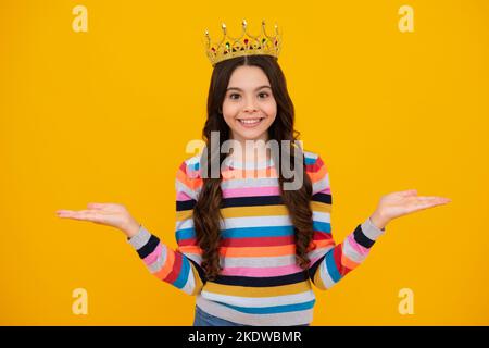 Piccola regina che indossa la corona d'oro. Ragazza adolescente principessa che tiene corona tiara. PROM partito, concetto di infanzia. Felice adolescente, positivo e sorridente Foto Stock