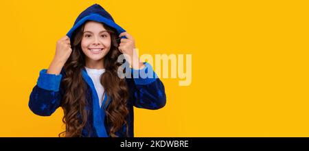 Ragazza felice che sorride in accappatoio con cappuccio sfondo giallo, abbigliamento da casa. Faccia del bambino, manifesto orizzontale, ritratto isolato della ragazza adolescente, bandiera con Foto Stock