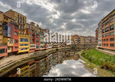 Una vista sui colorati edifici lungo il fiume di Girona che si riflettono sul fiume Onya Foto Stock