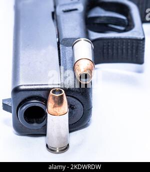 Una pistola nera da 9mm mm con due proiettili a punta cava da 9mm mm su sfondo bianco Foto Stock