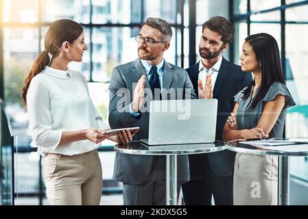 Passiamo ora al concetto: Un gruppo di colleghi che utilizzano un notebook insieme in un ufficio moderno. Foto Stock