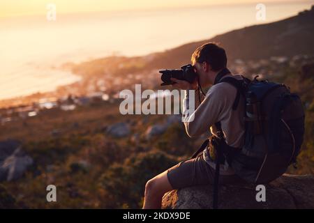 Scegli la tua avventura: Un giovane fotografo che fotografa dalla cima di una montagna. Foto Stock