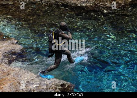 29 maggio 2022, Larnaca, Cipro: Un subacqueo salta nella laguna blu del Mar Mediterraneo al Parco Nazionale della Foresta di Capo Greco, all'estremità meridionale della Baia di Famagosta, e fa parte del comune di Ayia Napa. La Repubblica di Cipro si trova a un crocevia storico-culturale tra Europa e Asia. Le sue principali città, la capitale di Nicosia, Limassol, Famagosta e Paphos, hanno assorbito le influenze di generazioni di conquistatori, pellegrini e viaggiatori e hanno un'aria cosmopolita e provinciale. Oggi Cipro è una popolare destinazione turistica per i visitatori provenienti dall'Europa, favorita da Foto Stock