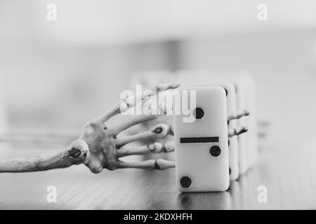 Mano scheletro e ossa di domino sono sul tavolo, foto in bianco e nero, gioco di morte, gioco d'azzardo Foto Stock