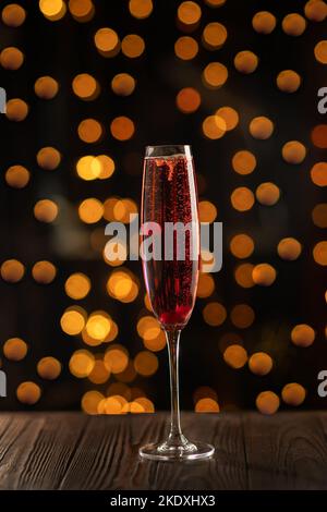 Cocktail Kir Royal Champagne su sfondo di legno, spazio copia. Bicchiere di flauto con spumante e bacca di champagne per festeggiare Foto Stock