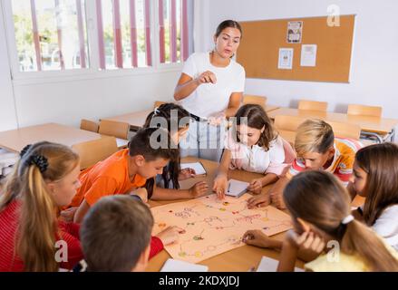 Insegnante femminile e scolaresche che giocano a un gioco da tavolo durante la lezione Foto Stock