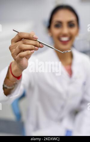 Diamo un'occhiata più da vicino. Ritratto di una giovane dentista che tiene uno strumento chirurgico. Foto Stock