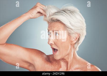 Donna anziana con sorpresa, capelli bianchi in studio sfondo grigio e viso scioccato a taglio di capelli sani. Acconciatura corta in età avanzata, vecchia signora con Foto Stock