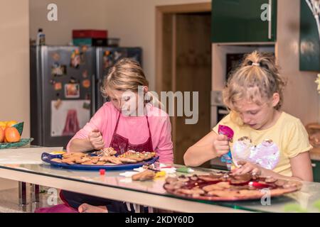 le ragazze dei bambini amabili che cucinano i biscotti del pan di zenzero per la tabella di natale Foto Stock