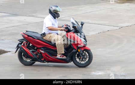 SAMUT PRAKAN, THAILANDIA, 29 2022 SETTEMBRE, Un uomo con casco cavalca una moto sulla strada della città Foto Stock