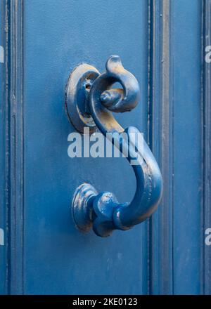 Vista in primo piano della maniglia in ottone vintage dipinto con bella patina isolato su antica porta in legno blu brillante, Montpellier, Francia Foto Stock