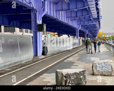 New York, NY, USA - 9 novembre 2022: Pedoni che camminano sotto la FDR Drive lungo l'East River a Lower Manhattan Foto Stock